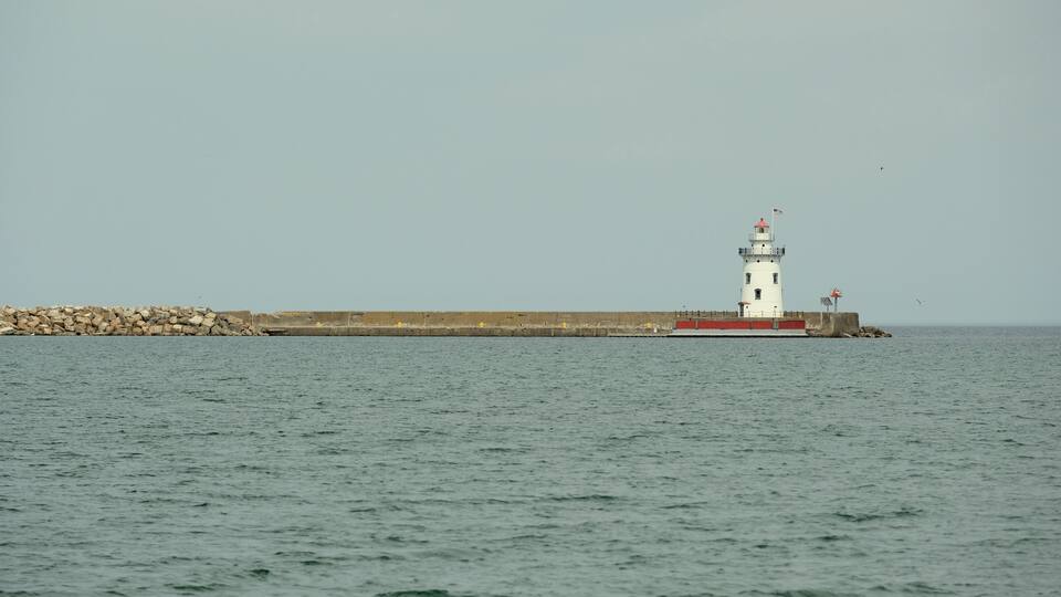 A lighthouse by a rocky breakwater in the sea.