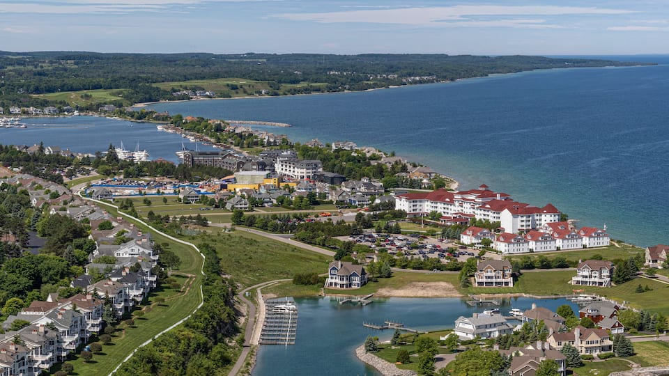 An aerial view of a coastal town with a marina, residential areas, and a large body of water.