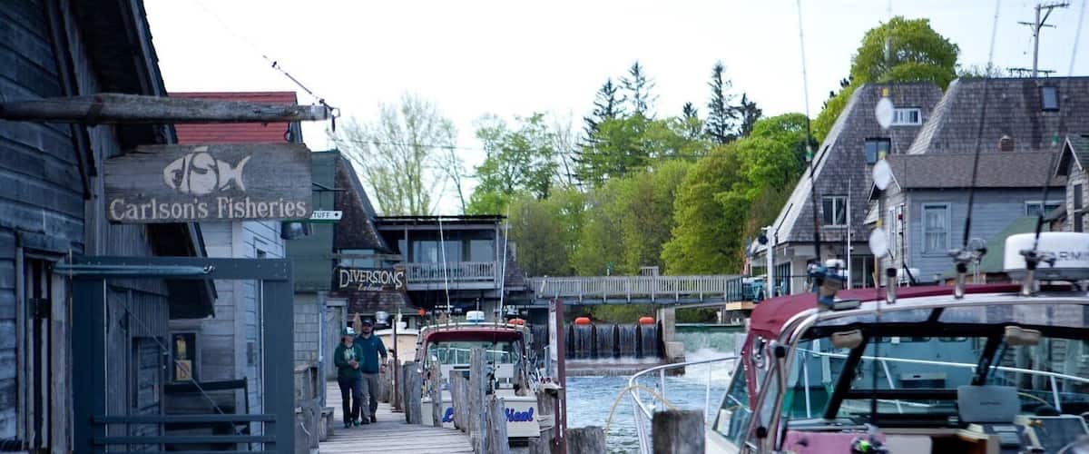 Un quai avec des bateaux, une passerelle en bois et une enseigne indiquant « Carlson's Fisheries ».