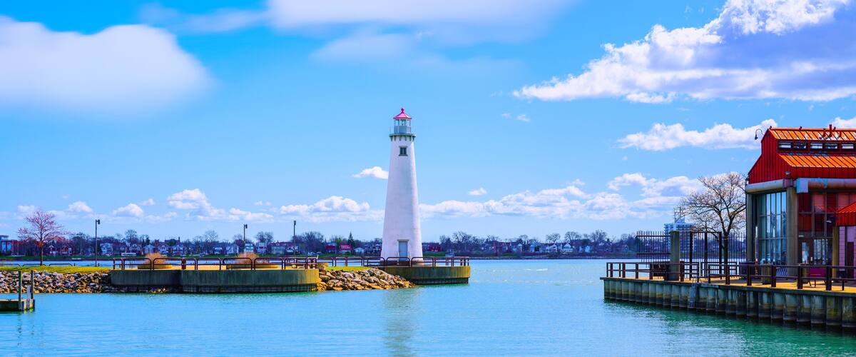A lighthouse on a pier with a clear blue sky and calm water.