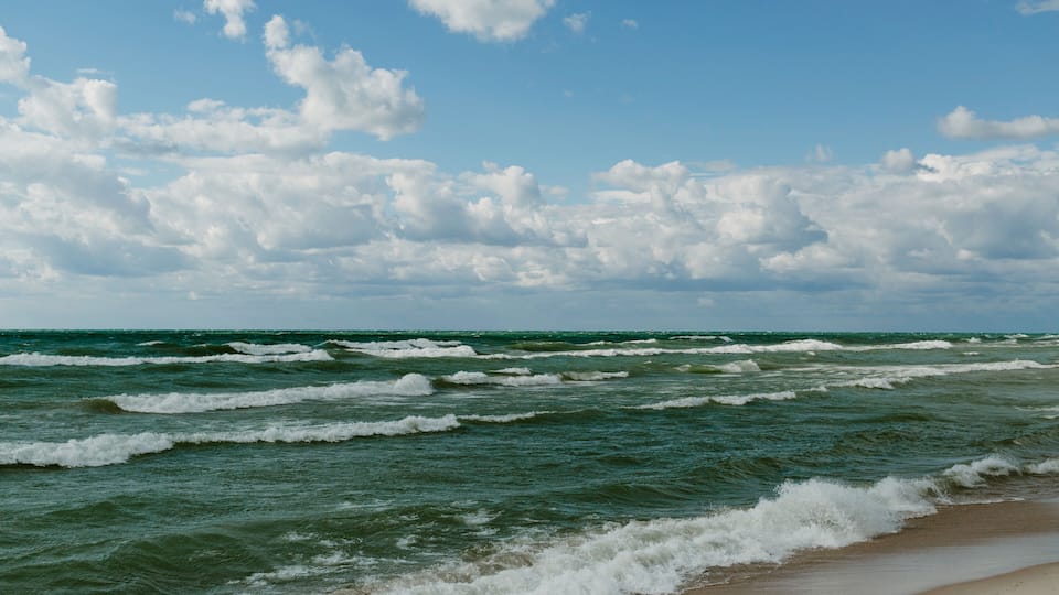 A beach with waves and a cloudy sky.