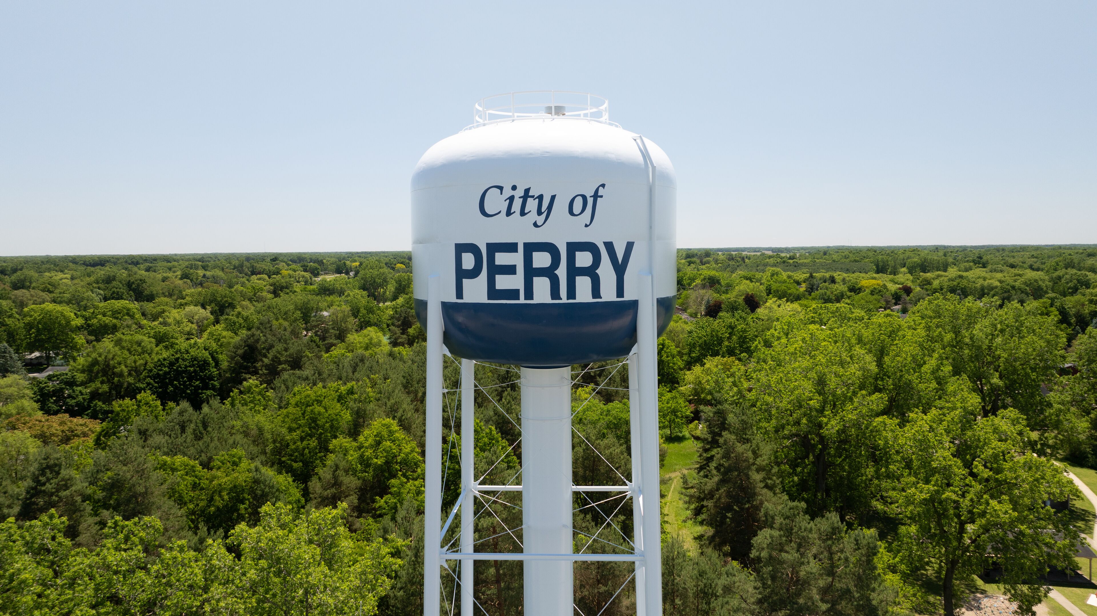 A water tower labeled "City of Perry" with a forested landscape in the background.