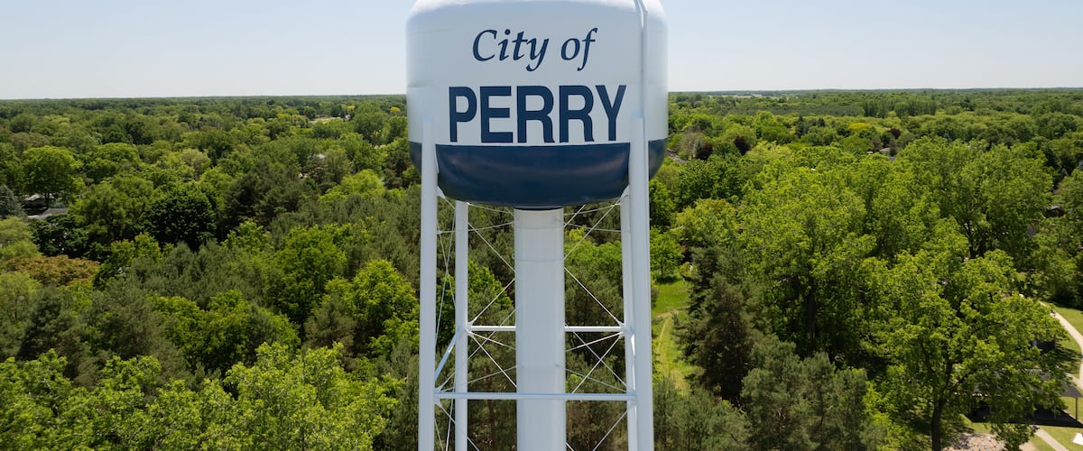 A water tower labeled "City of Perry" with a forested landscape in the background.