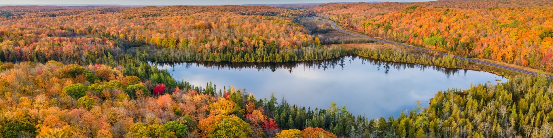 Un lago rodeado de árboles de colores otoñales y un camino sinuoso.