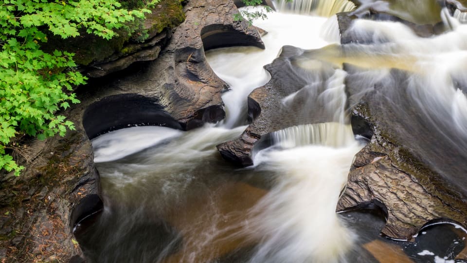 A waterfall cascading over rocks with surrounding greenery.