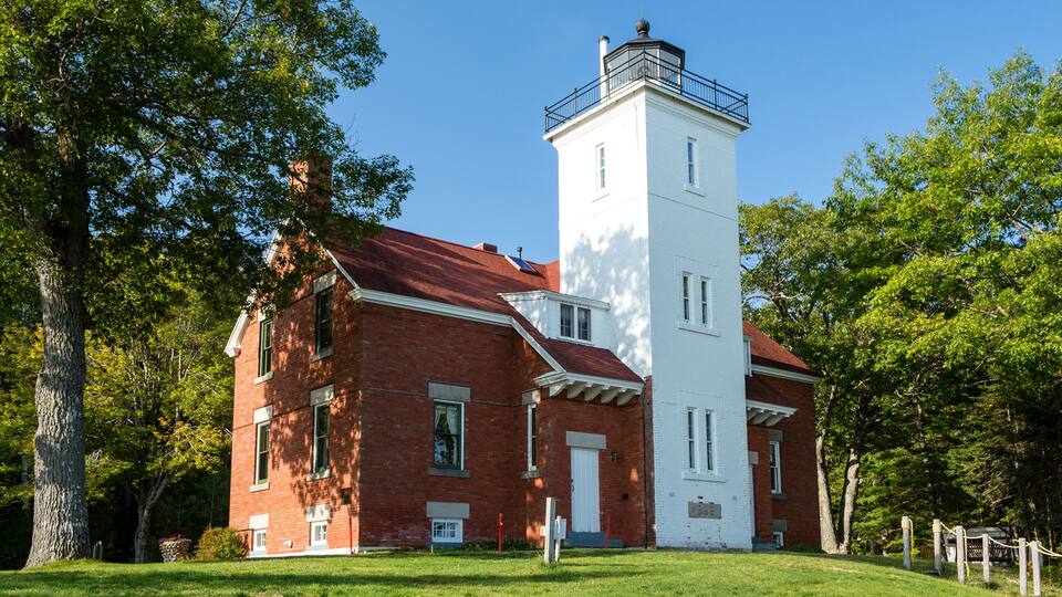A historic brick building with a white tower and a red roof.