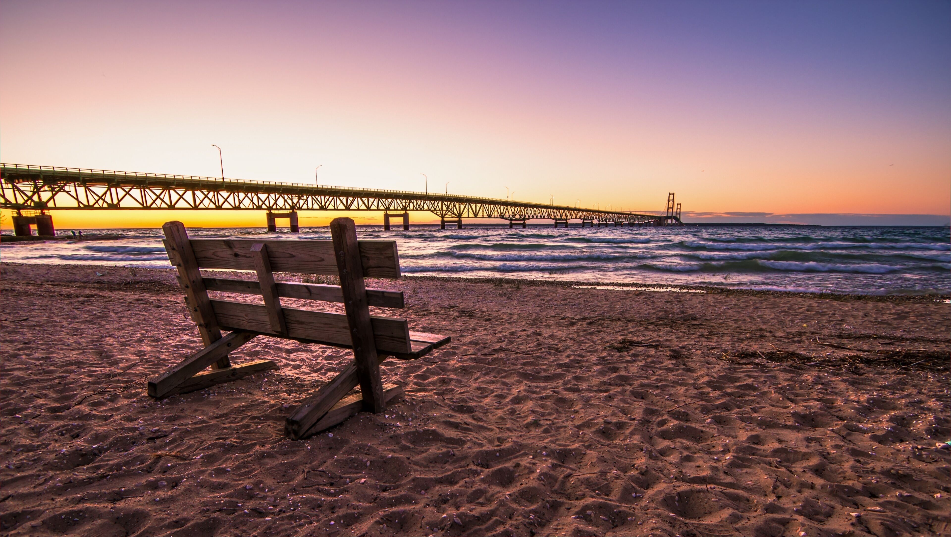 Mackinaw Bridge Twilight.. Park bench on the shores of the Mackinac Straits with the Mackinaw Bridge at the horizon.