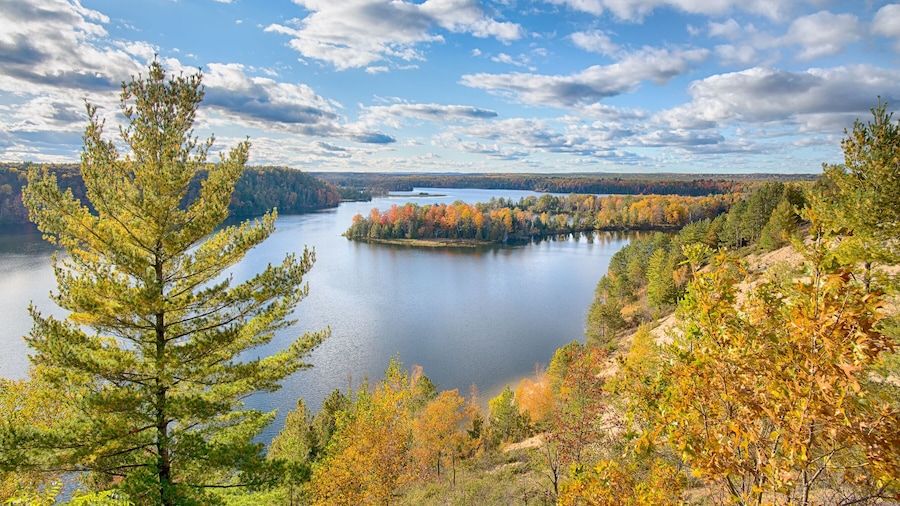 A lake surrounded by autumn-colored trees and a clear sky.