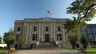 A historic courthouse with a flagpole, steps, and benches.