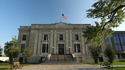 A historic courthouse with a flagpole, steps, and benches.