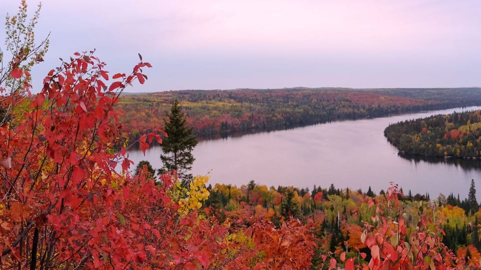 A lake surrounded by autumn-colored trees and distant hills.