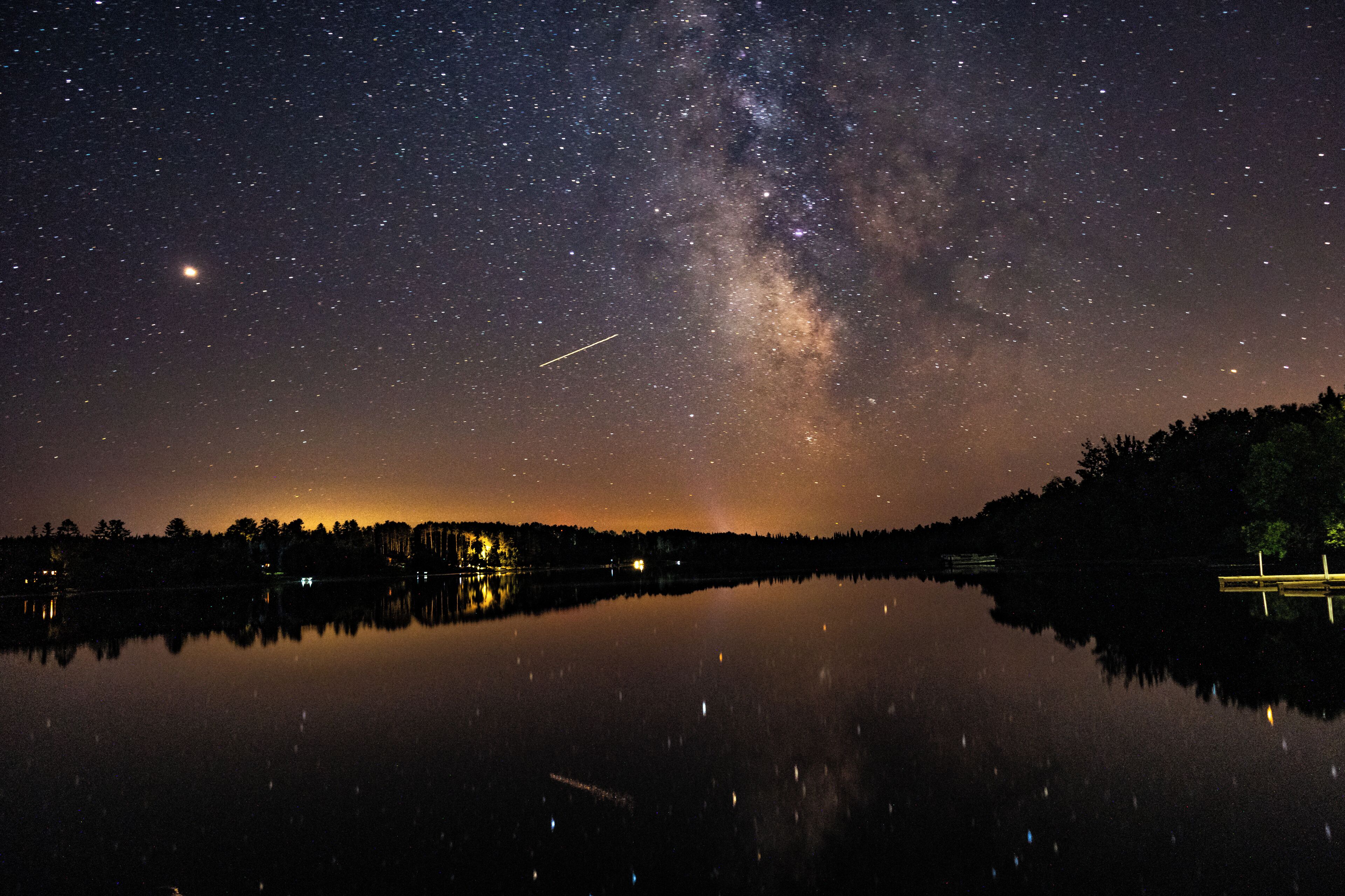 A starry night sky over a calm lake with the Milky Way visible.