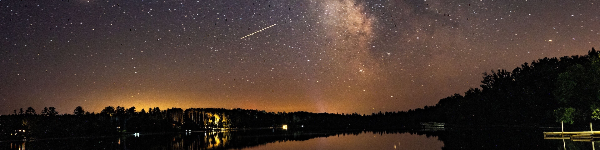 A starry night sky over a calm lake with the Milky Way visible.
