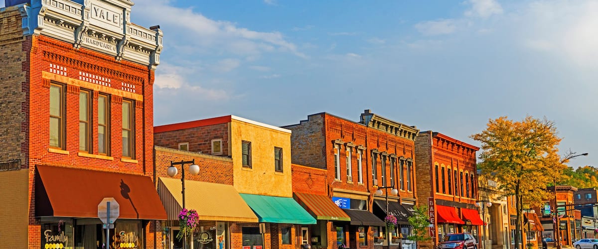 A street lined with historic buildings, including a hardware store and a bakery.