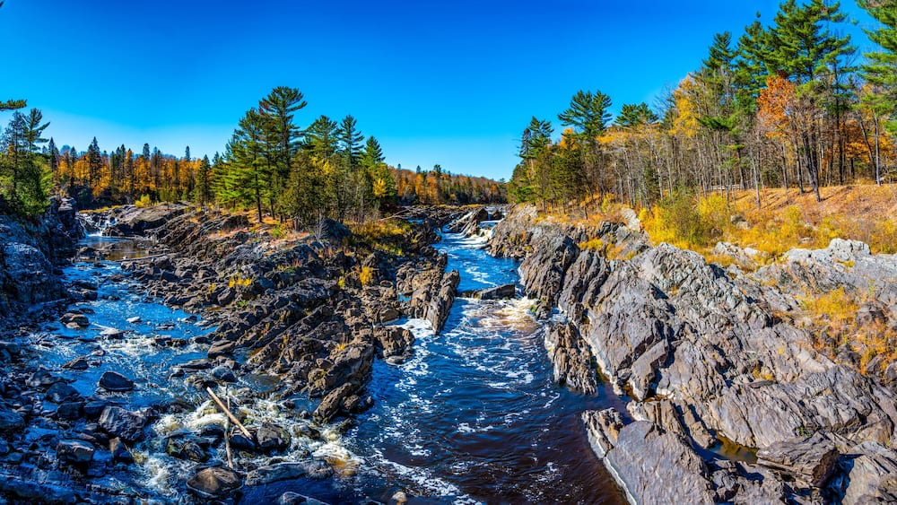A river flowing through a rocky gorge with dense forests on either side.