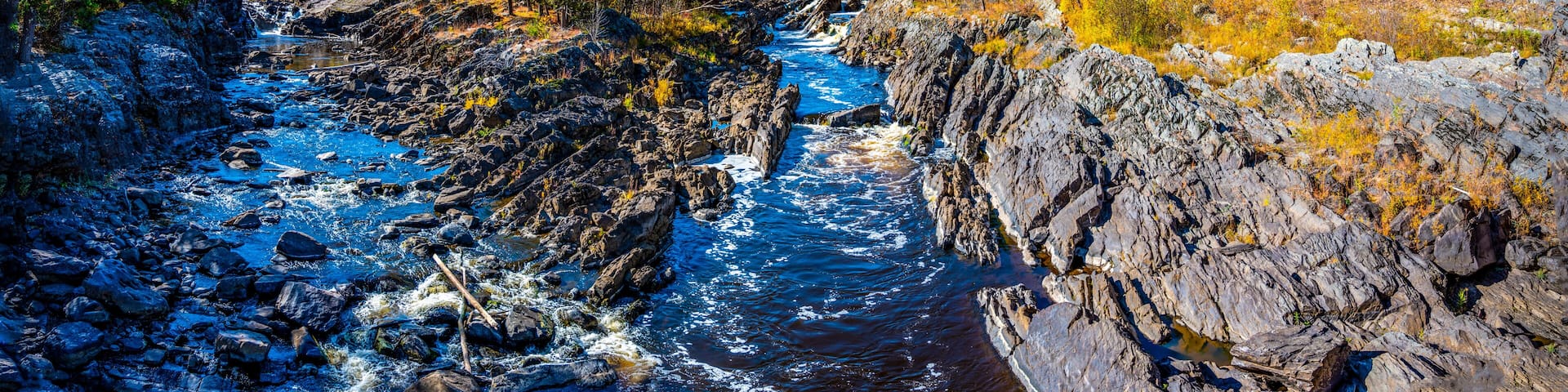A river flowing through a rocky gorge with dense forests on either side.