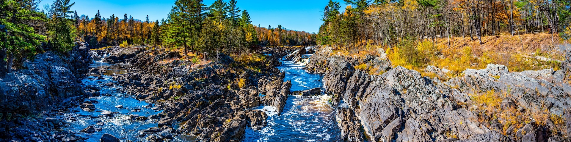 A river flowing through a rocky gorge with dense forests on either side.