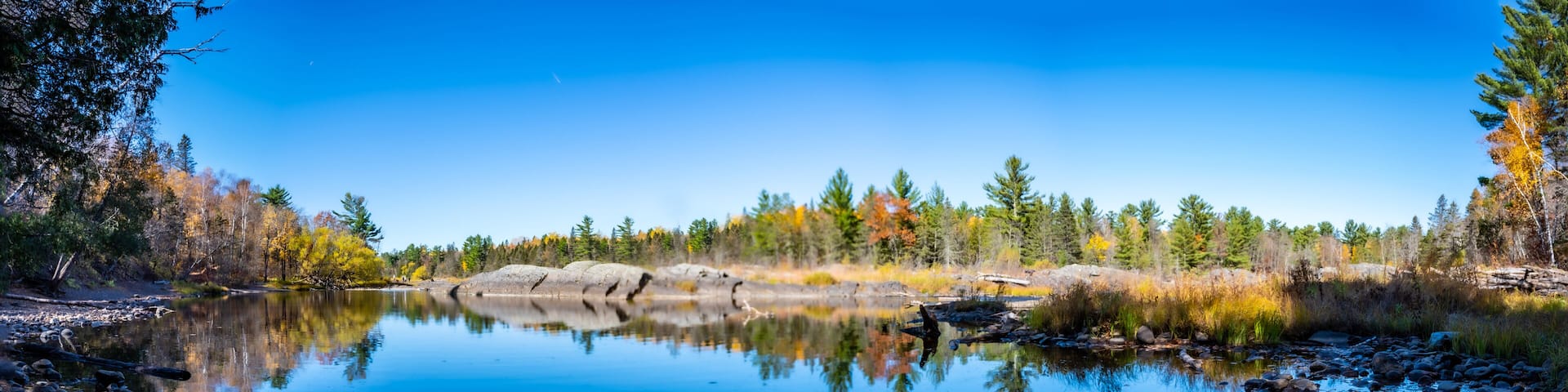 A calm lake surrounded by autumn-colored trees and rocks.