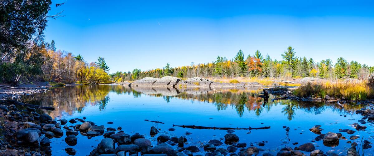 A calm lake surrounded by autumn-colored trees and rocks.