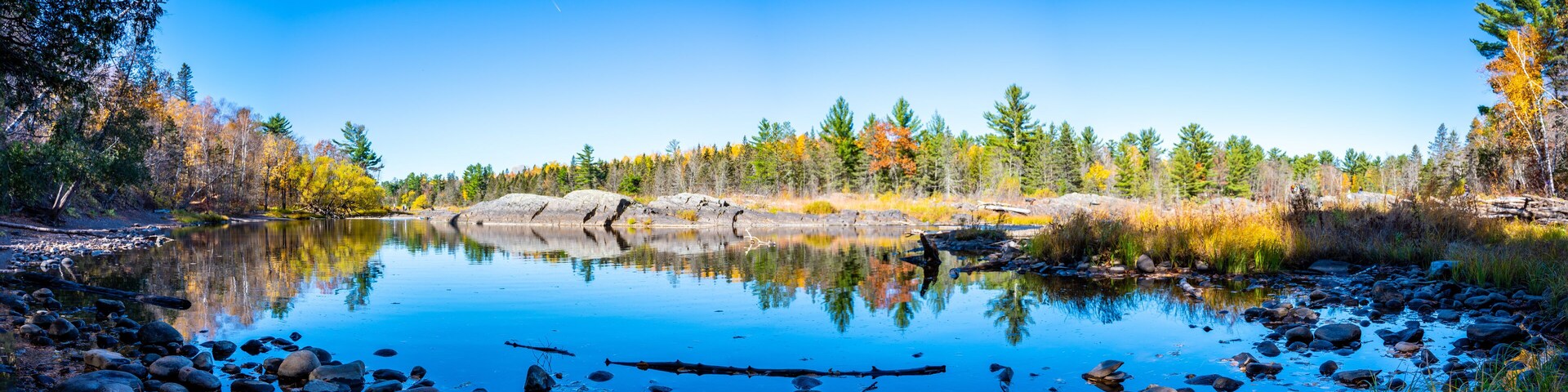 A calm lake surrounded by autumn-colored trees and rocks.