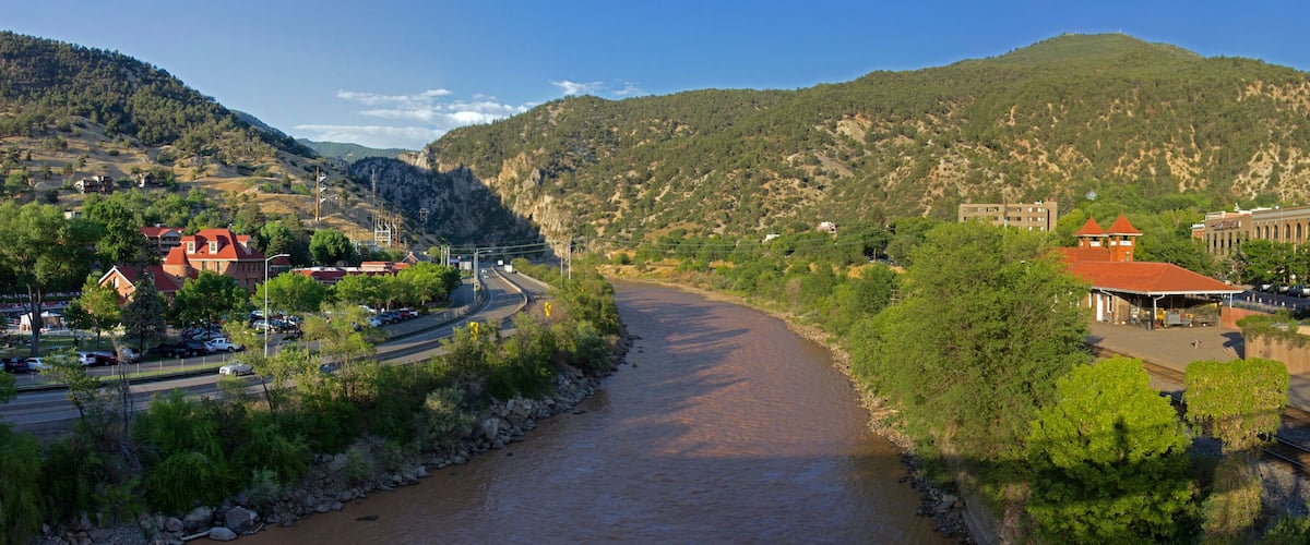 A river flowing through a town with mountains in the background.