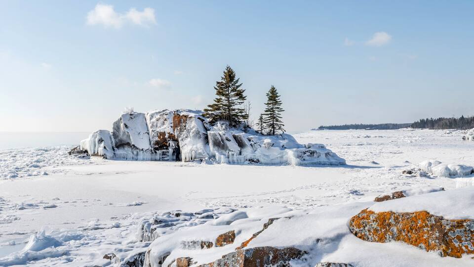 A snowy landscape with ice formations and trees.