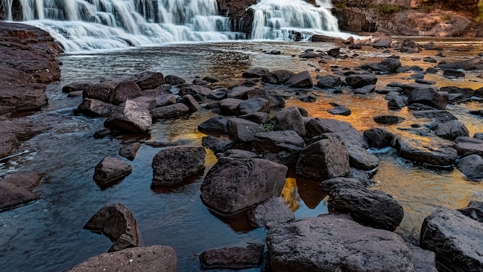 A rocky riverbed with multiple waterfalls.