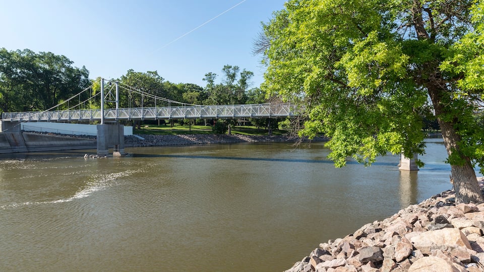 A suspension bridge over a river, surrounded by trees and rocks.