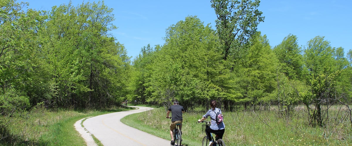 Man and woman riding bicycles on the North Branch Trail at Bunker Hill Woods in Chicago