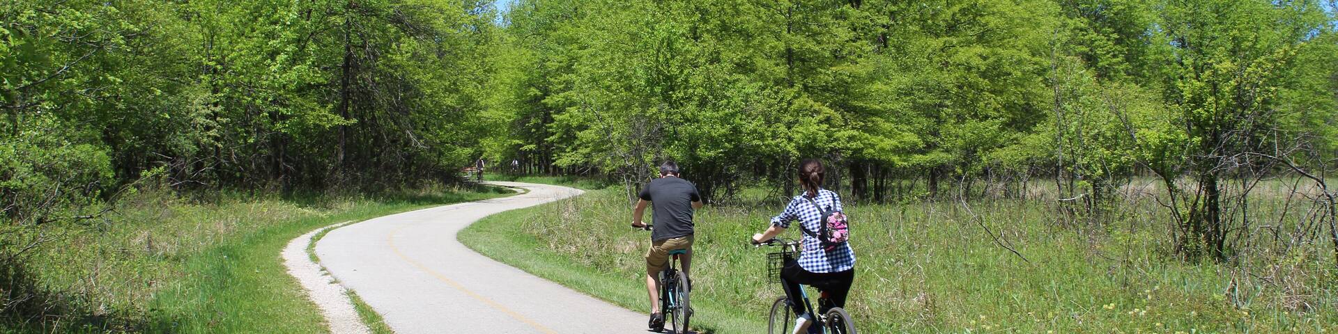 Man and woman riding bicycles on the North Branch Trail at Bunker Hill Woods in Chicago