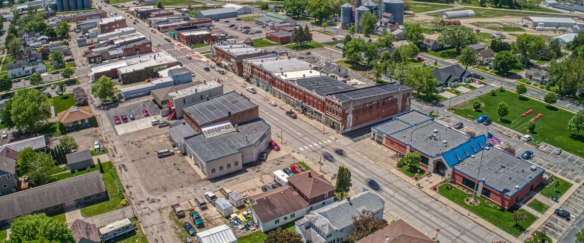 An aerial view of a town with industrial buildings, roads, and green areas.
