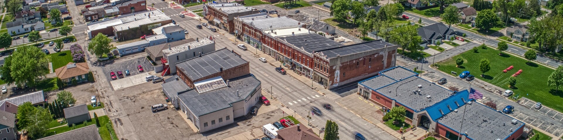An aerial view of a town with industrial buildings, roads, and green areas.