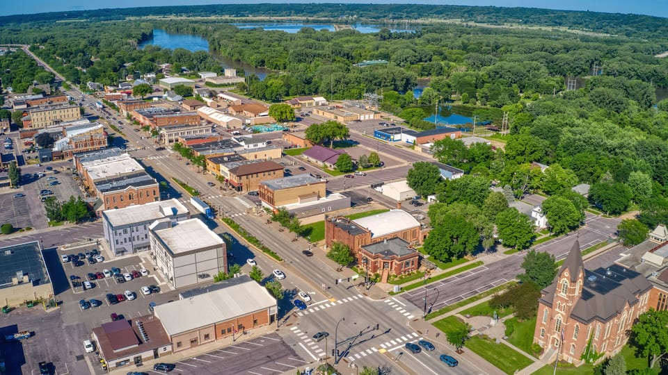 An aerial view of a town with a river, green parks, and historic buildings.