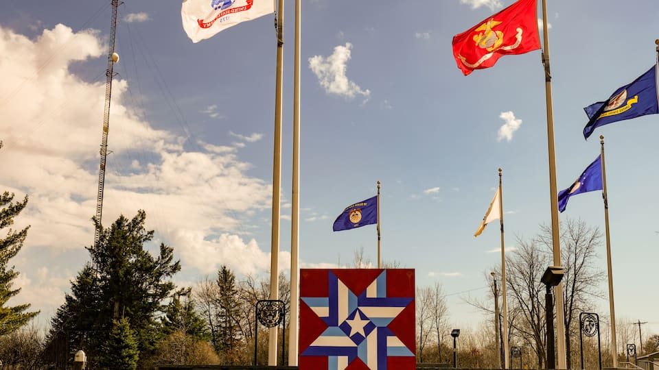 A flagpole with multiple flags, a star emblem, and a clear sky.