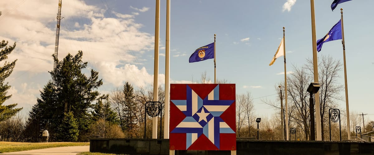 A flagpole with multiple flags, a star emblem, and a clear sky.
