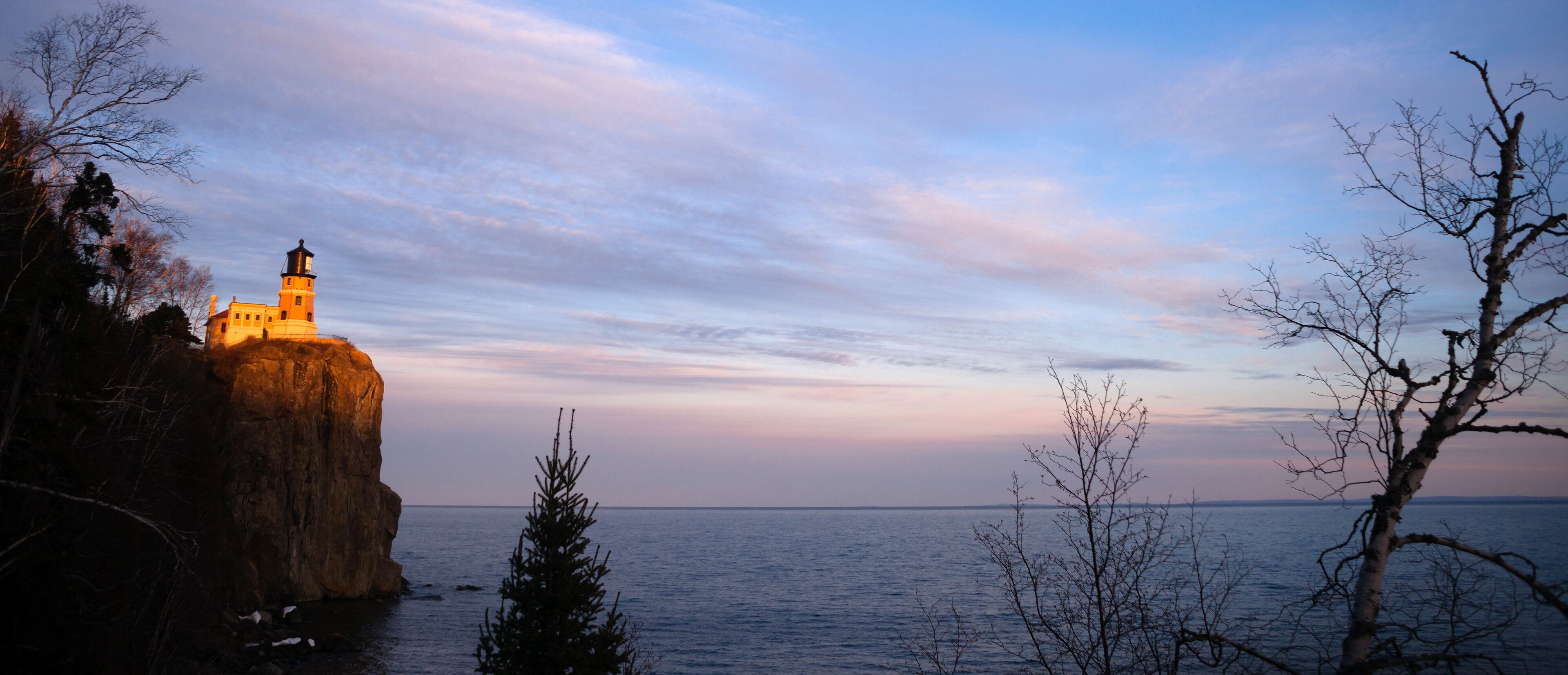 A lighthouse on a cliff by the sea with a clear sky.