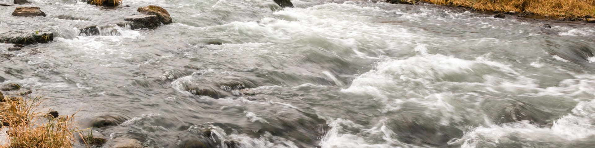 A fast-flowing river with a waterfall in the background.