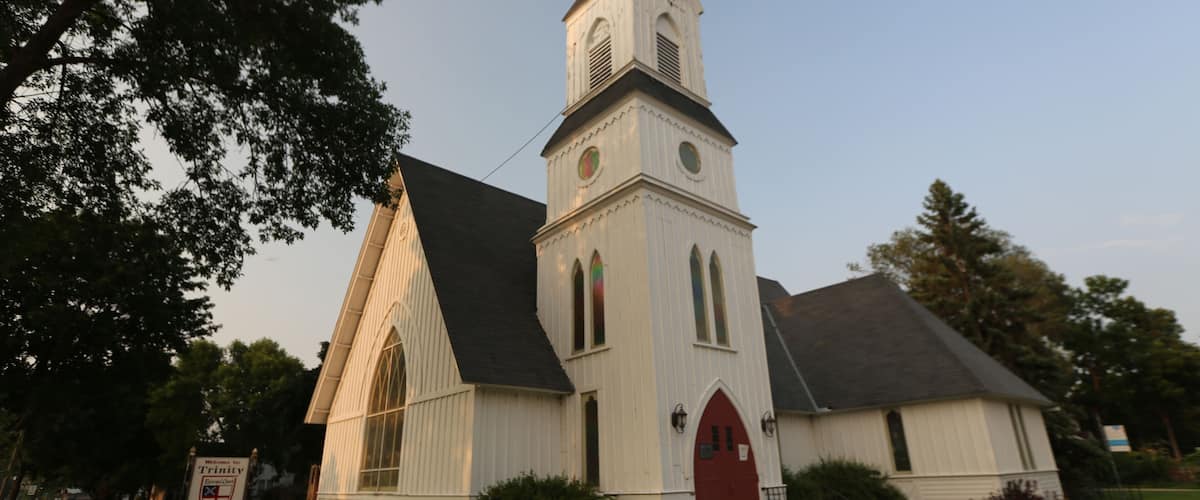 A white church with a steeple and a red door.