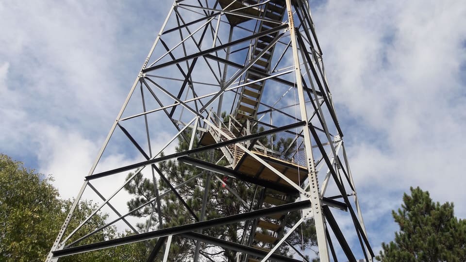 A tall metal structure with a staircase against a blue sky with clouds.