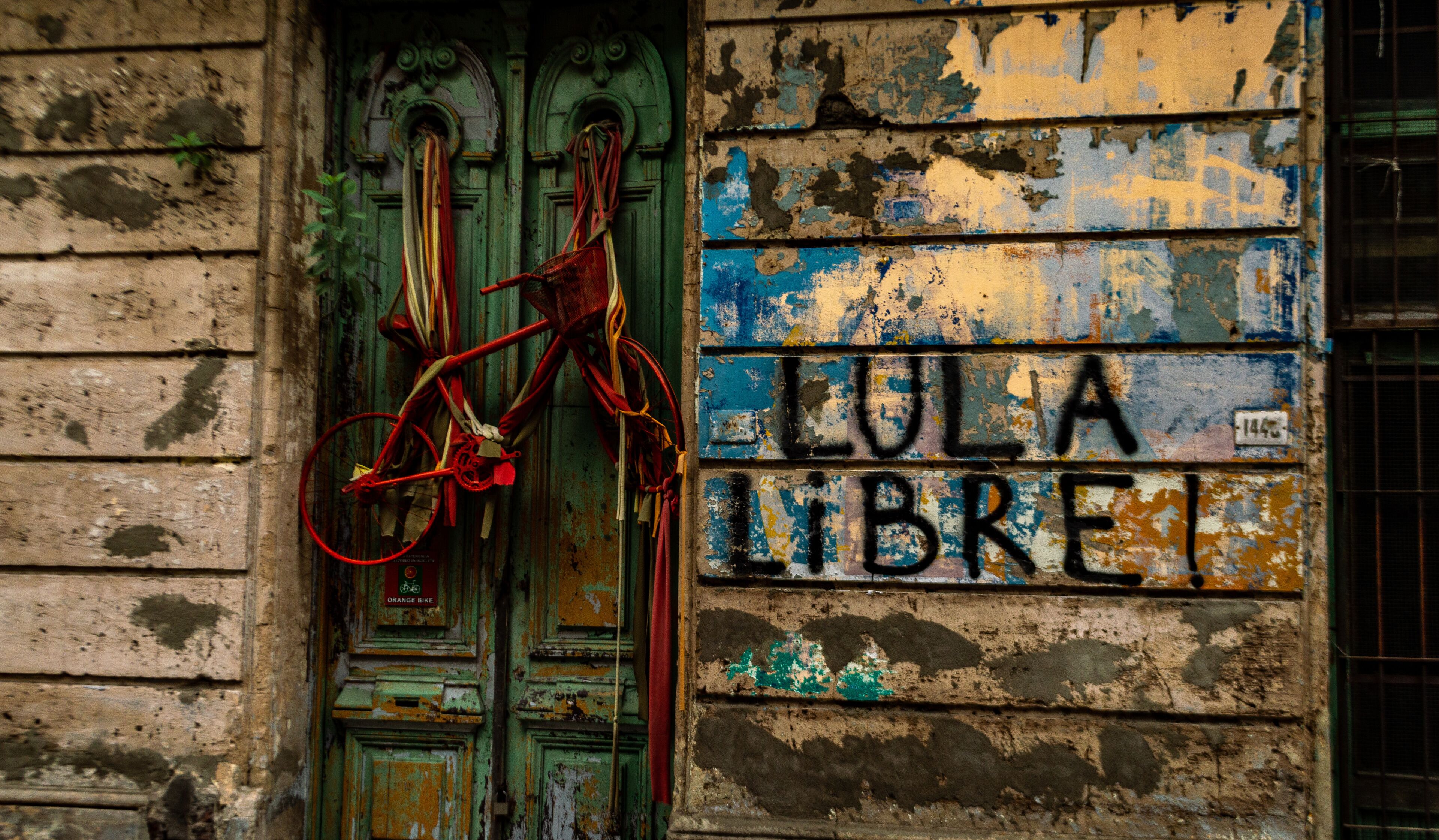 A weathered building with a green door and a sign reading "LULA LIBRE".