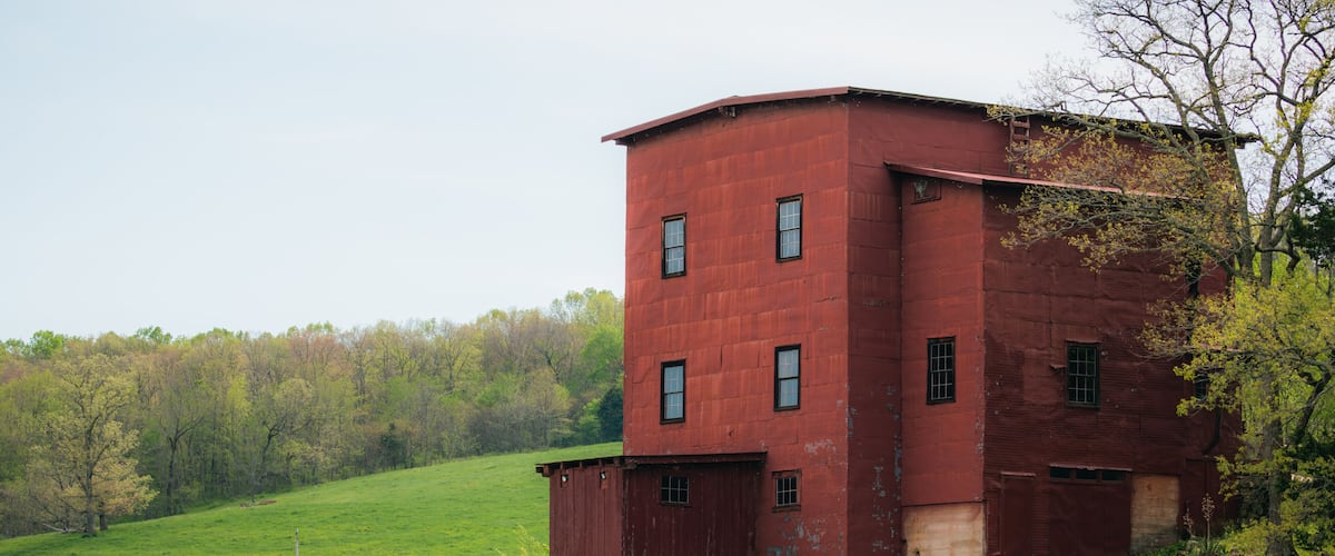 A red watermill by a waterfall in a green valley.