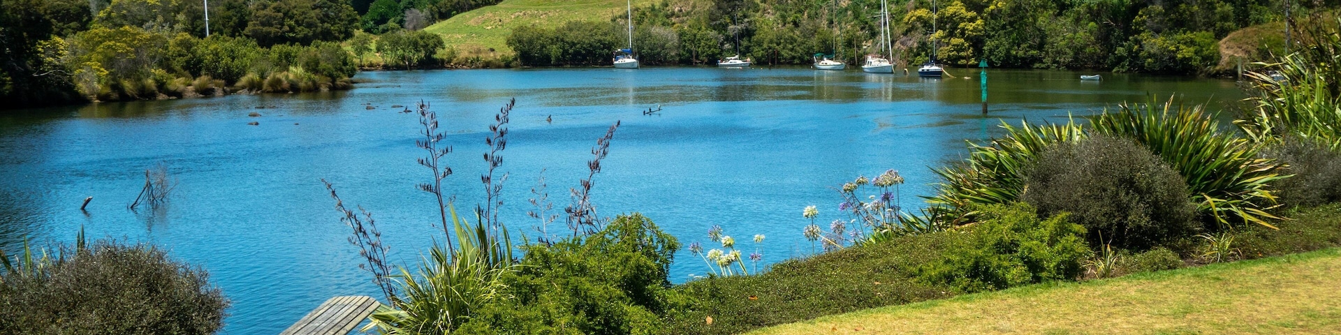 Un lago con barcos, rodeado de abundante vegetación y colinas.