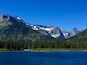 Una cordillera con picos nevados, bosques densos y un lago tranquilo.