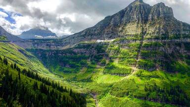 A mountainous landscape with a prominent peak, lush green valleys, and a river.