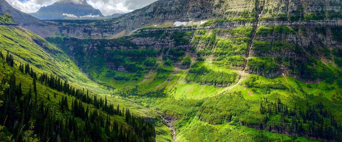 A mountainous landscape with a prominent peak, lush green valleys, and a river.