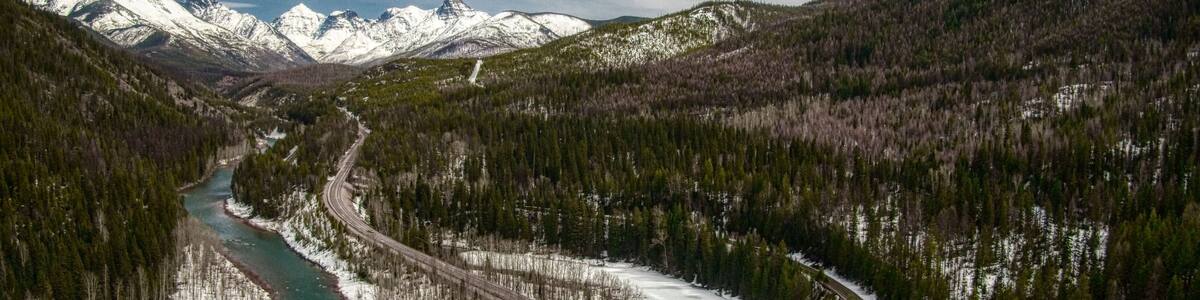 Snow-capped mountains with a river and forest in Essex, Montana, USA