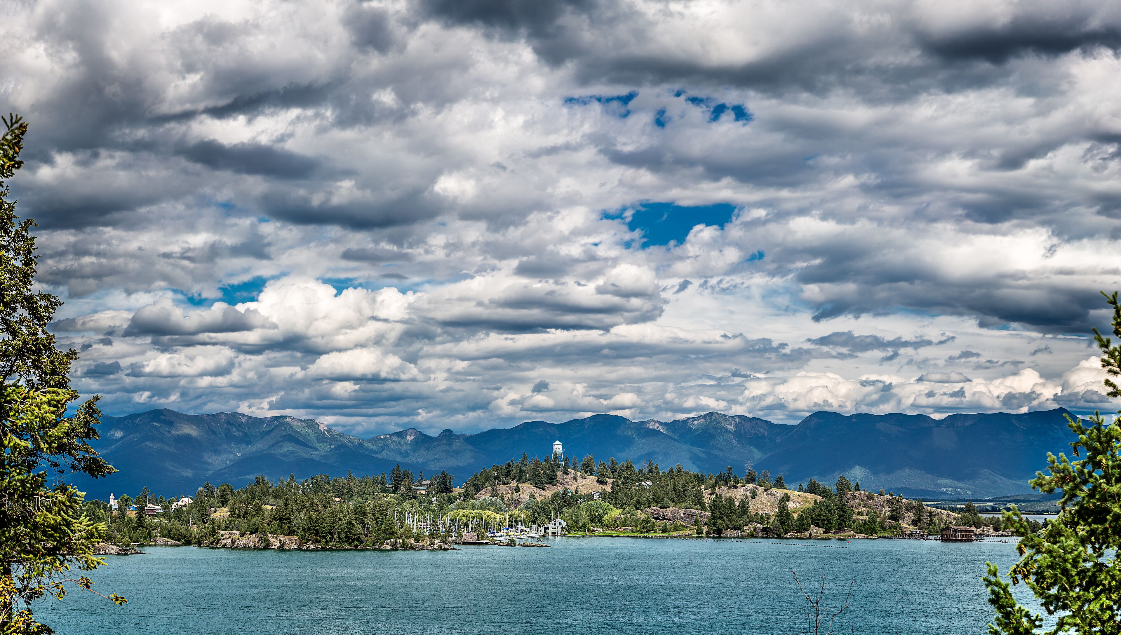 A lake with mountains in the background and a small town with houses and a church.