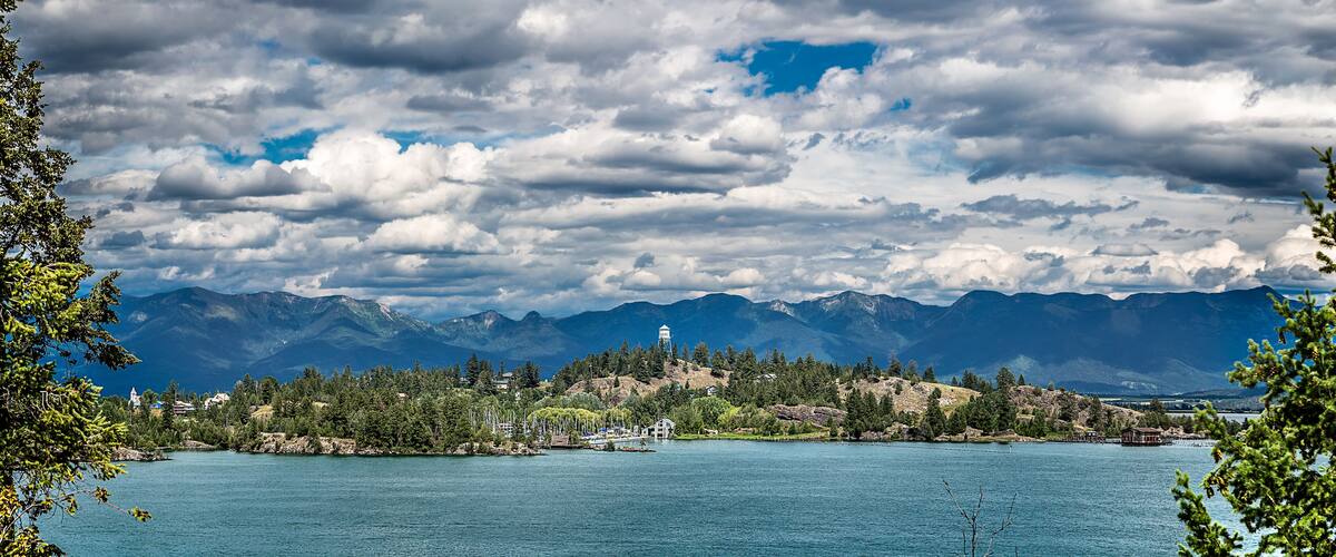 A lake with mountains in the background and a small town with houses and a church.