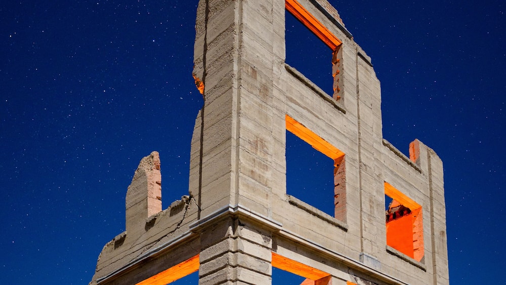 Un bùtiment historique aux murs en briques apparentes et aux touches de couleur orange, se dressant sous un ciel nocturne étoilé.