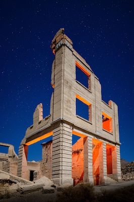 A historic building with exposed brickwork and orange accents, set against a starry night sky.